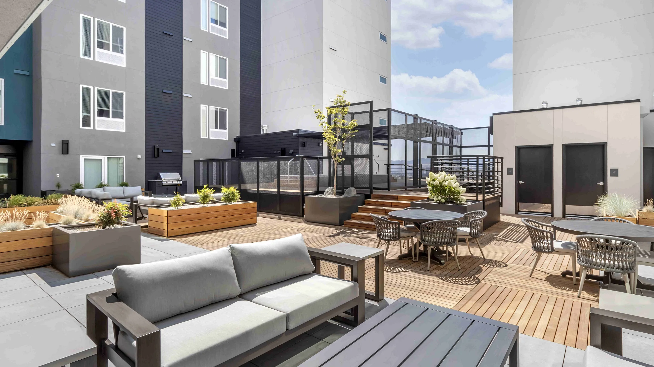 The Edison in Reno, NV apartment rooftop courtyard with stylish outdoor seating, lush planters, and sleek architectural design under a clear blue sky.