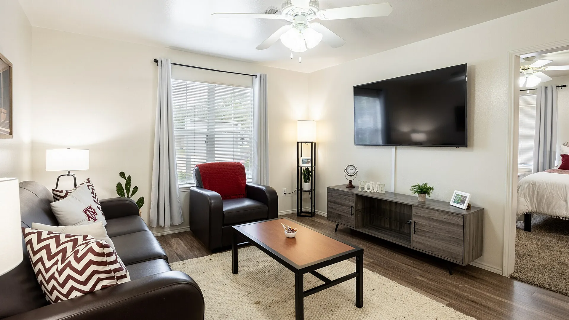 Furnished living room with leather furniture and flat screen TV at The Zone student apartments near Texas A&M in College Station TX