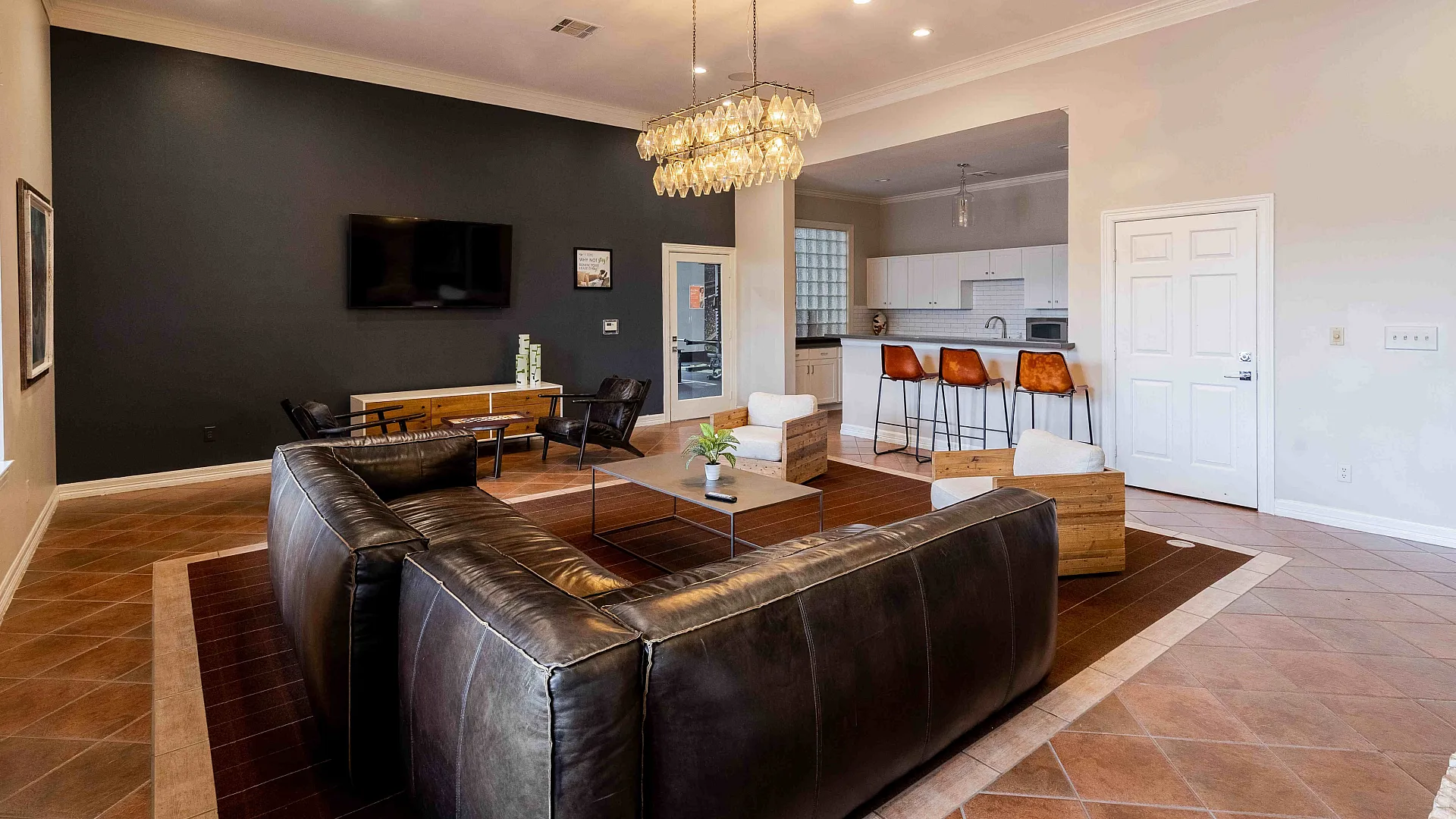 Open-concept living room and kitchen with leather seating at The Zone student apartments near TAMU in College Station Texas