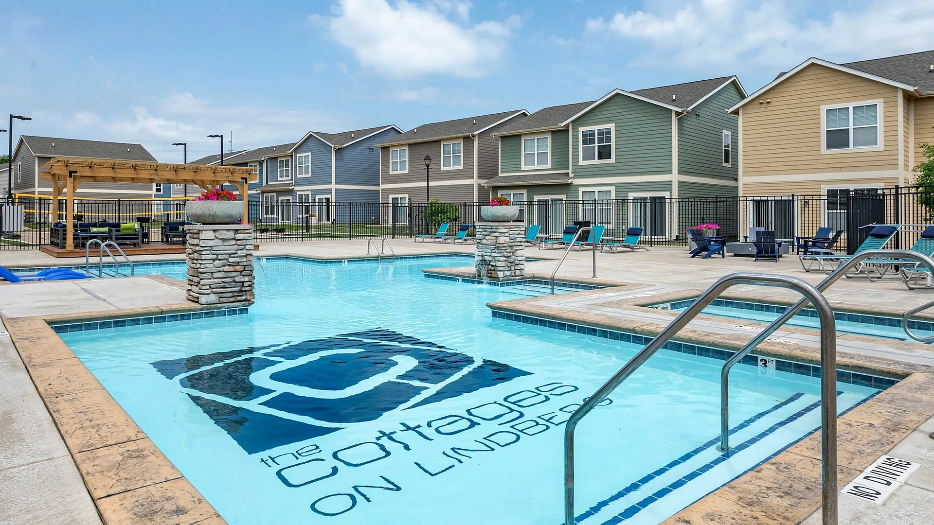 Inviting pool area at The Cottages on Lindberg with comfortable loungers and charming townhomes in West Lafayette, IN near Purdue