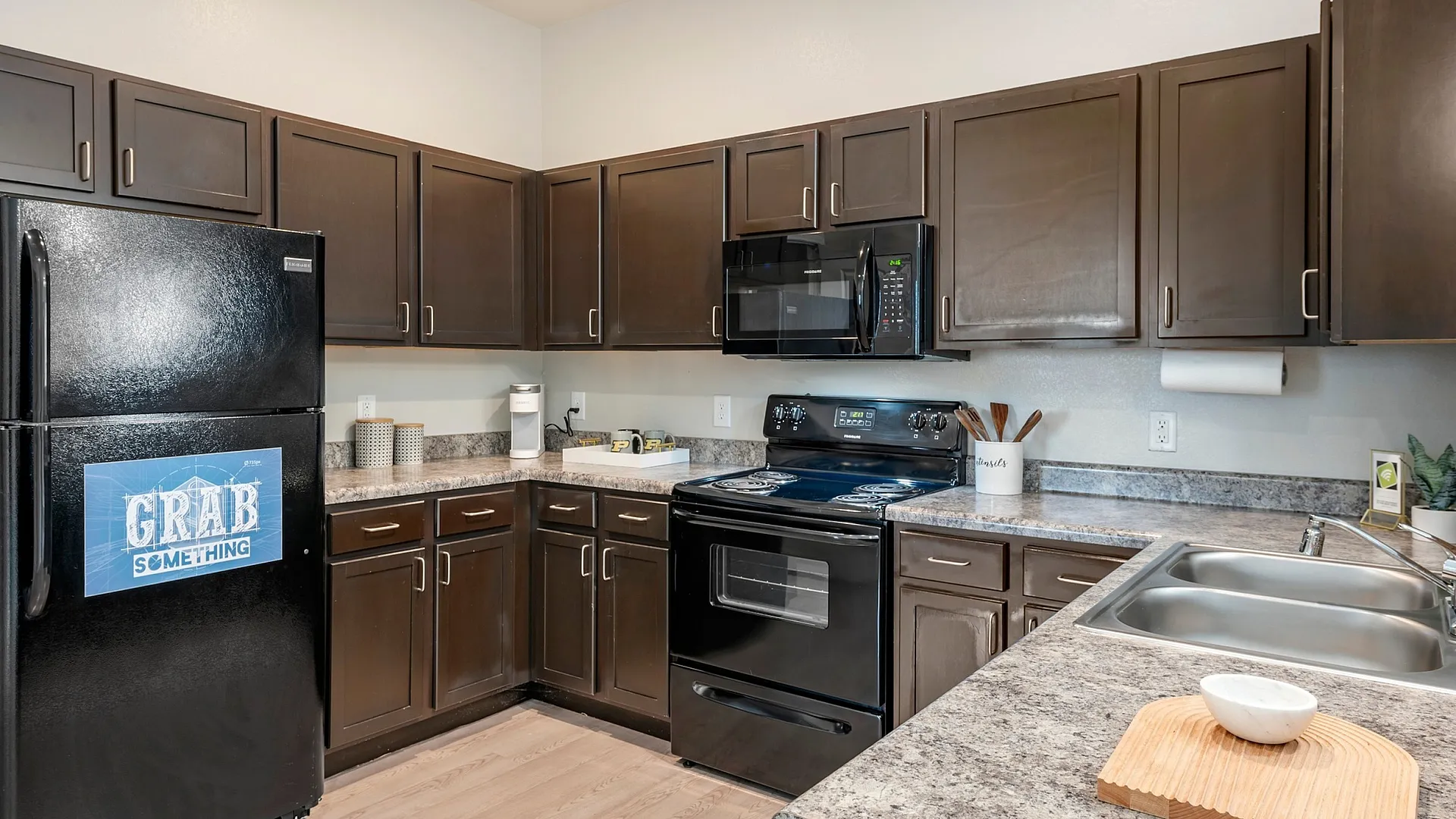 Contemporary kitchen with dark wood cabinets and sleek appliances at The Cottages on Lindberg in West Lafayette, IN