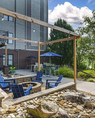 Outdoor patio lounge area with cozy fire pit and comfortable seating surrounded by greenery at The Landings Knoxville TN