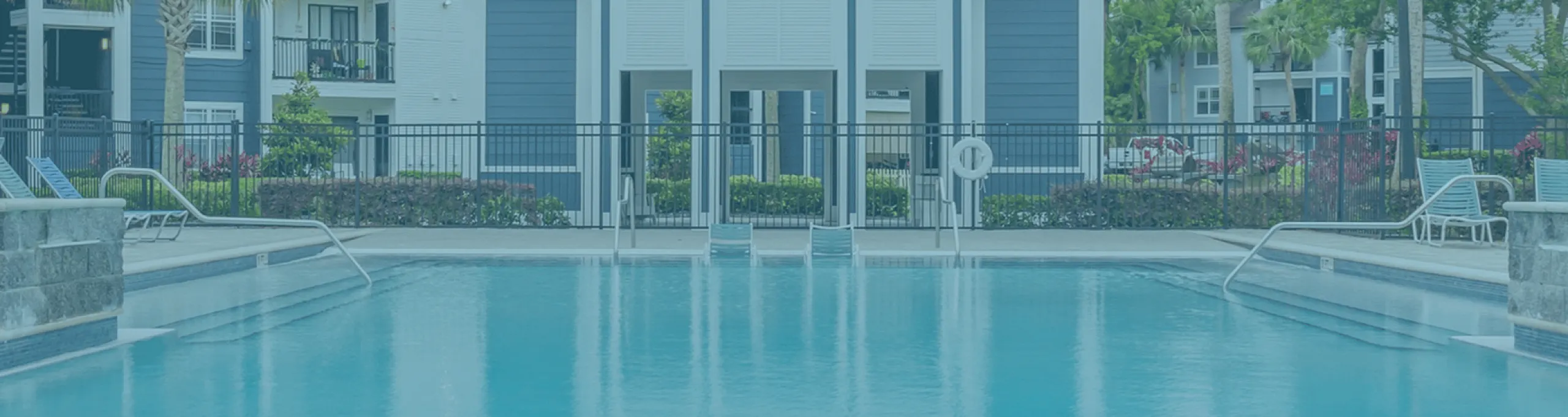 Phoenix Orlando apartment complex with a sparkling pool, surrounded by lush greenery and elegant architecture, perfect for relaxation.