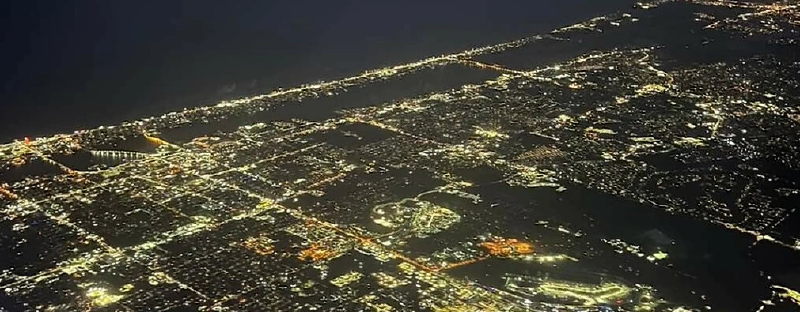 Breathtaking aerial view of a cityscape at night, illuminated by a sea of shimmering lights, highlighting a vibrant urban landscape.