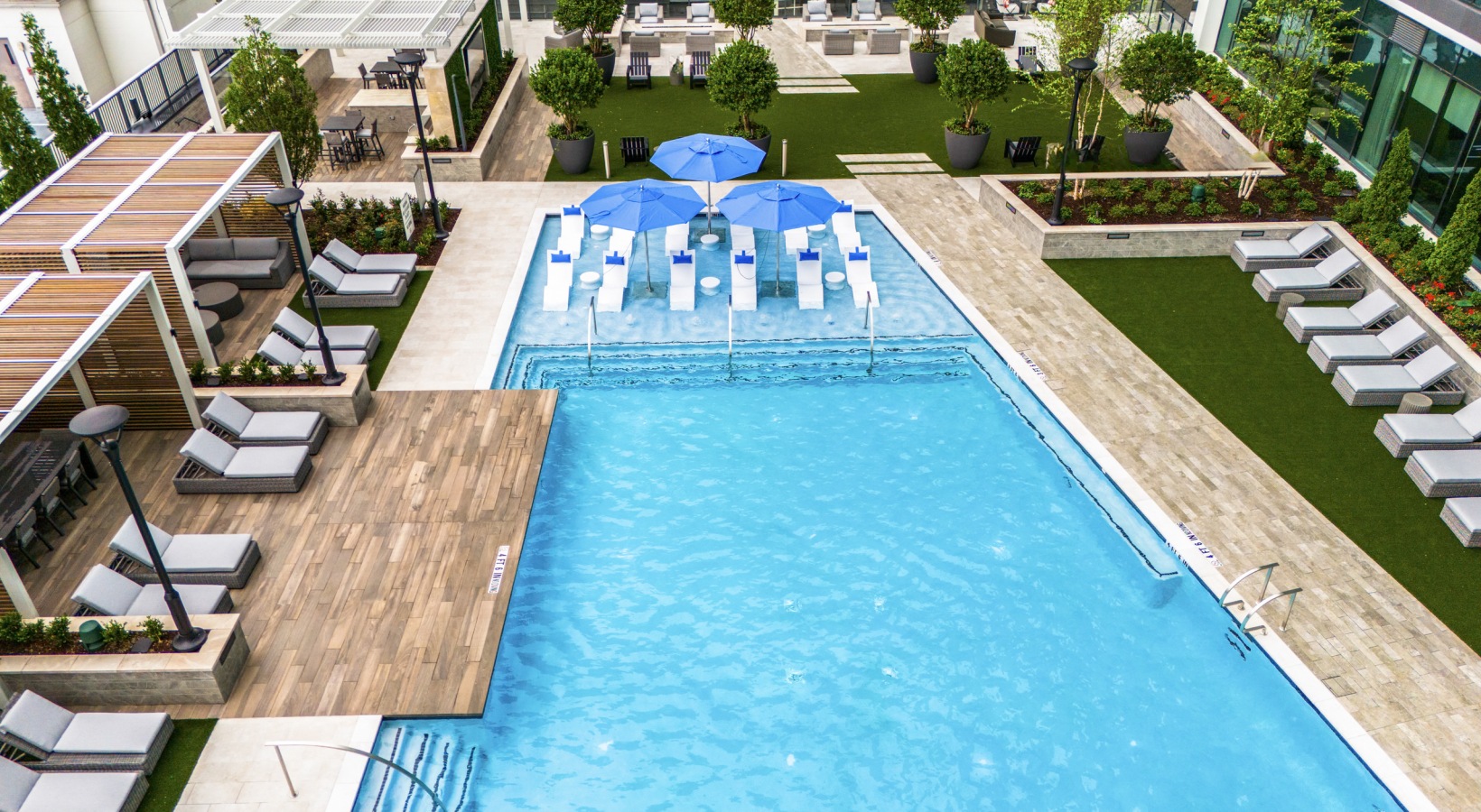 aerial view of pool deck with shaded seating areas and sun loungers