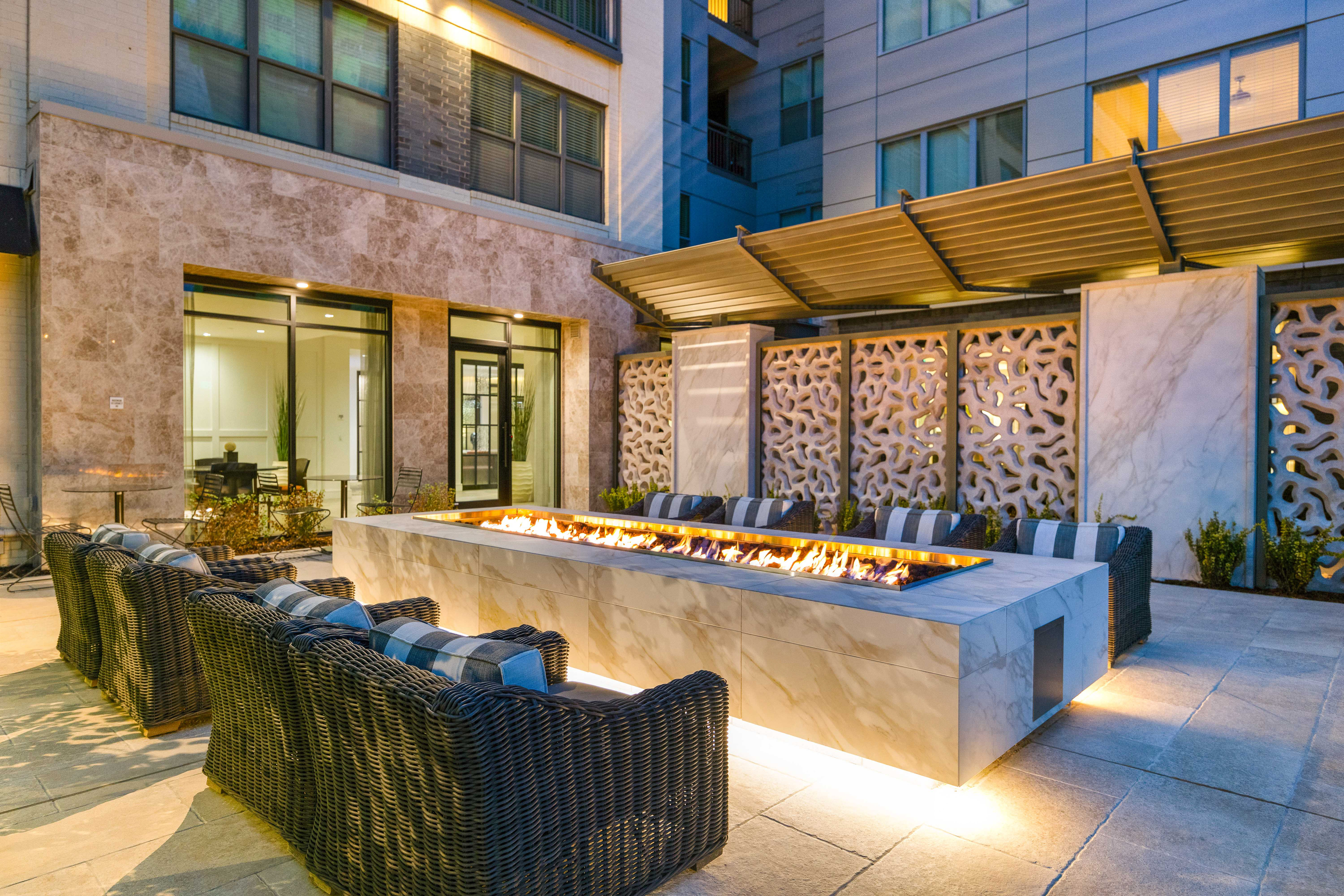 outdoor courtyard at apartment community with fire pit, wicker seating, and modern architectural accents.