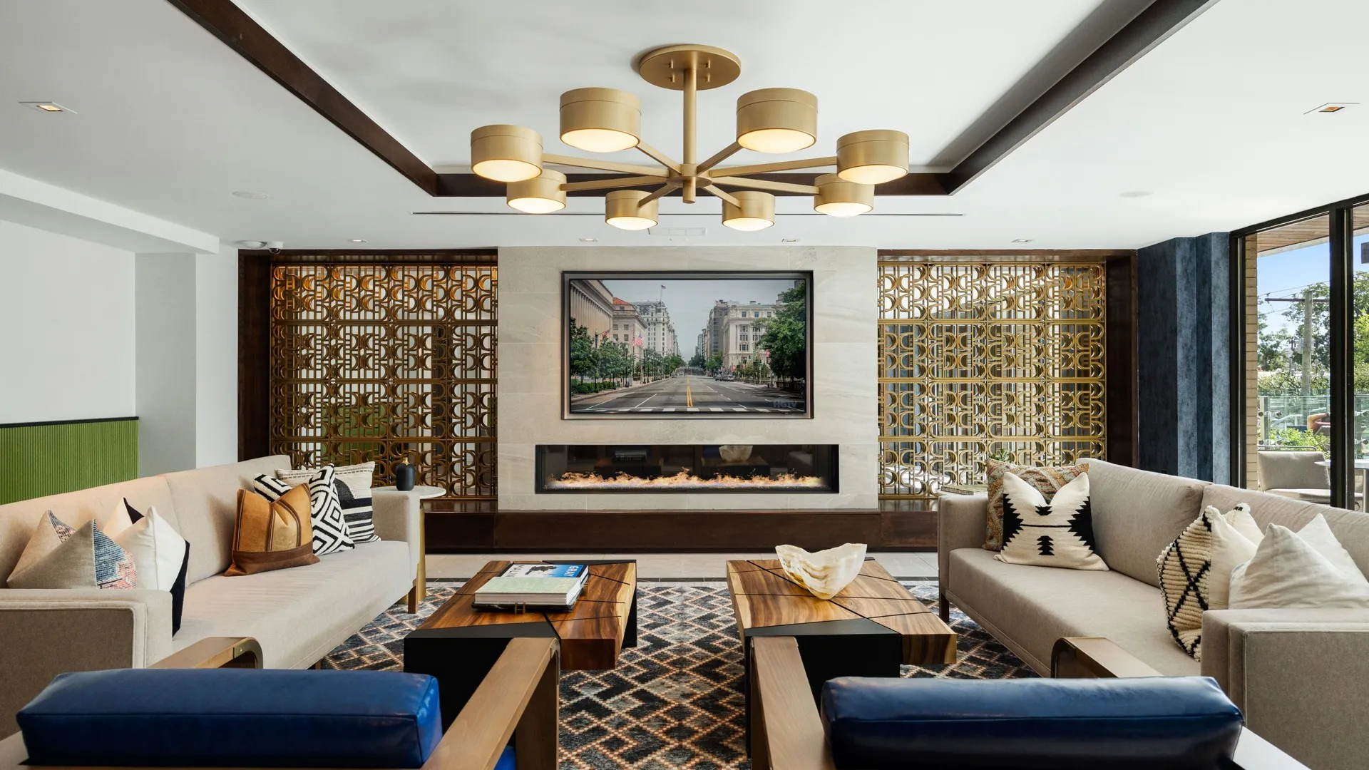 Resident club room with sofas and upholstered armchairs and coffee tables centered around a gas indoor fireplace