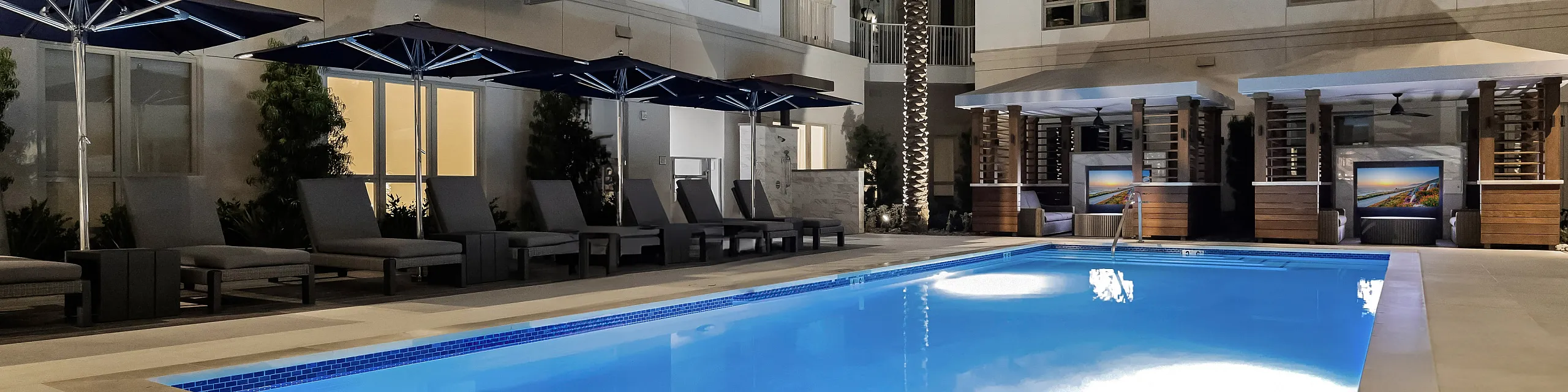 outdoor pool with chaise lounge chairs and 2 cabanas