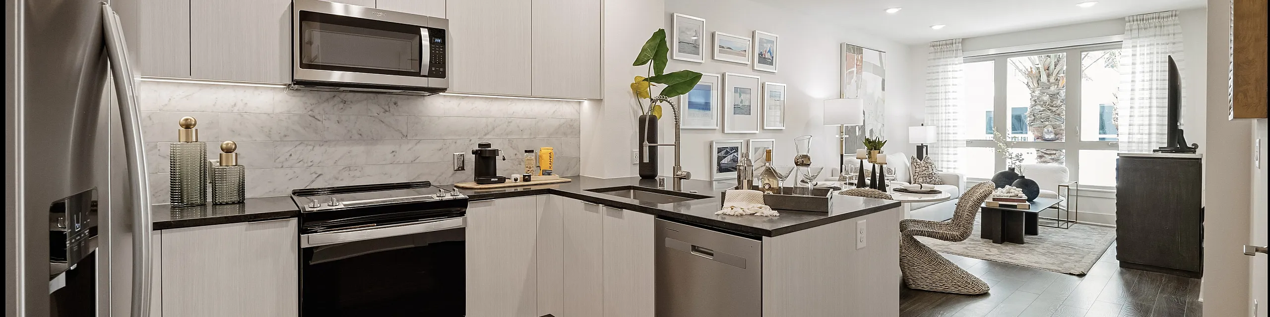 Kitchen photo with white wood cabinets and black countertops, dark brown wood flooring, and stainless steal appliances