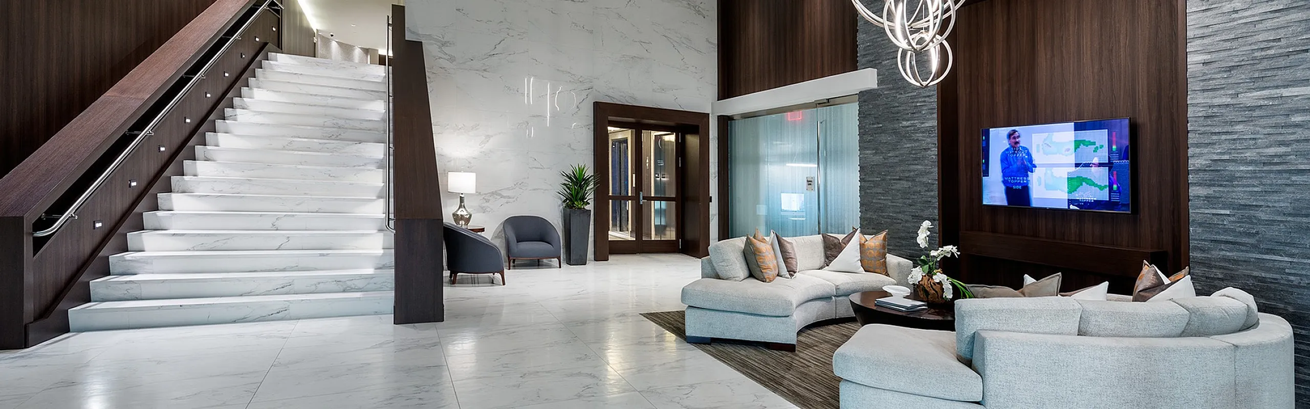 Luxurious lobby featuring elegant marble flooring, modern chandelier, and stylish seating area with sleek dark wood accents.