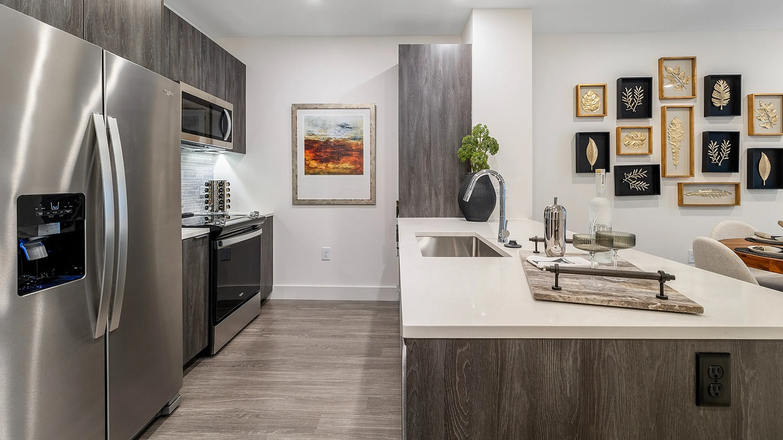 Modern kitchen with sleek stainless steel appliances, elegant dark wood cabinets, and stylish wall art, offering a luxurious dining area with sophisticated decor.