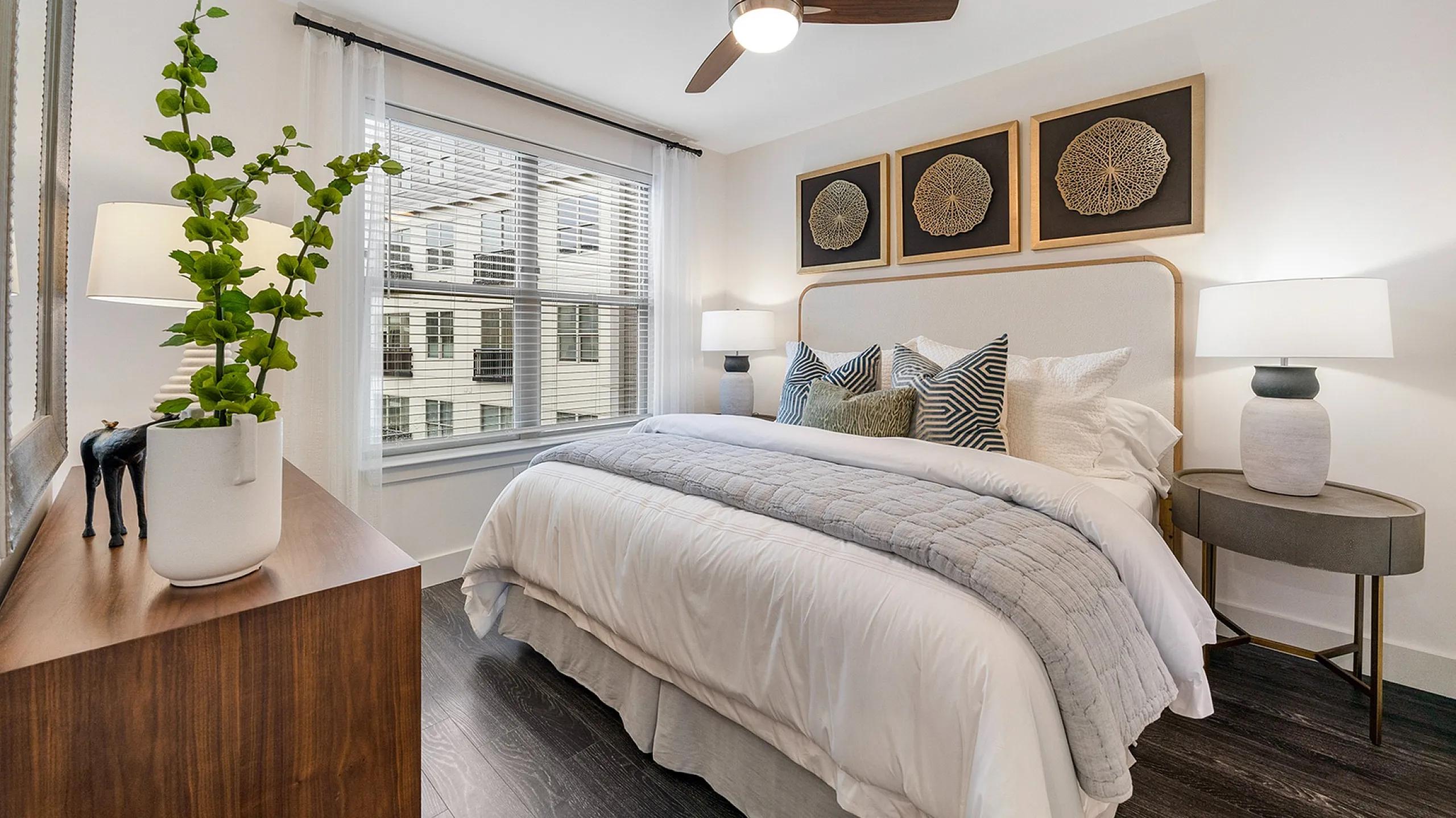 Inviting bedroom with a sleek floating bed, accent pillows, and modern decor, illuminated by natural light through large windows.