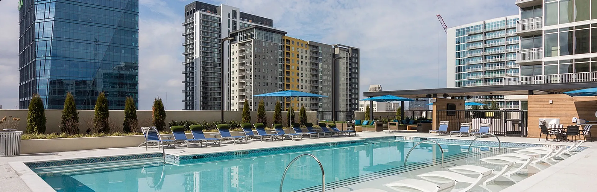 Luxurious rooftop pool with scenic city views, surrounded by modern high-rise buildings and elegant poolside loungers.