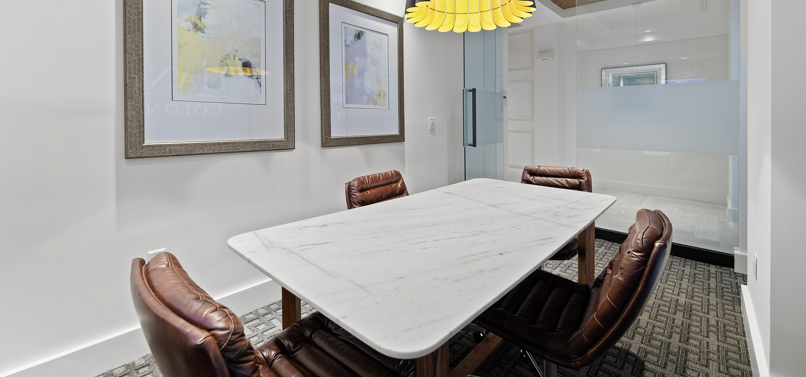 Elegant dining area with a modern marble table and chic leather chairs, illuminated by a stylish pendant lamp, perfect for sophisticated gatherings.