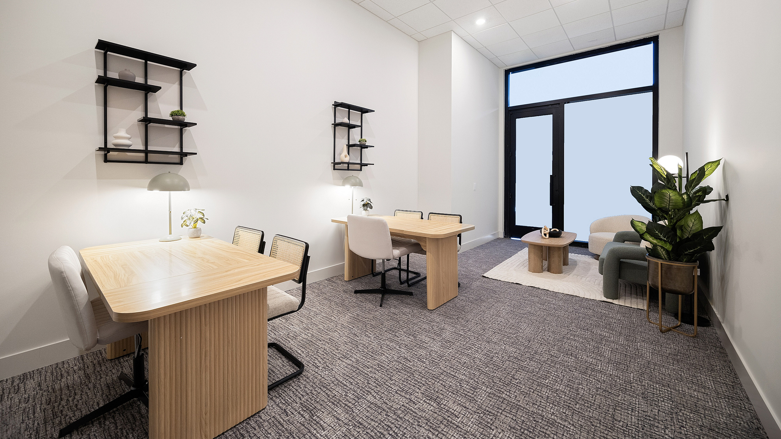 Modern office space with sleek wooden desks, stylish chairs, and elegant decor, illuminated by soft lighting and natural light from large windows.