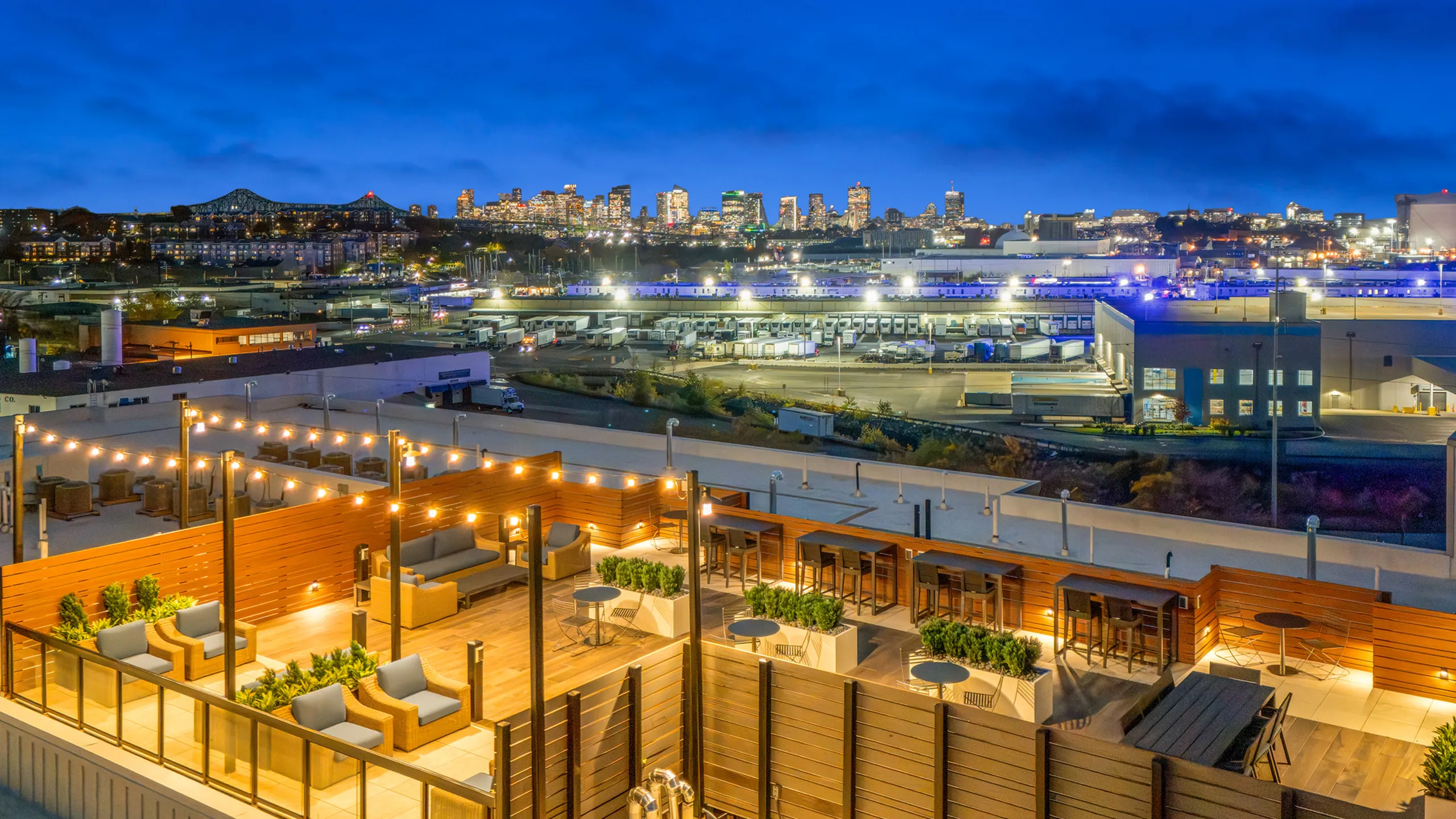Vibrant rooftop terrace with cozy seating and string lights, offering breathtaking cityscape views.