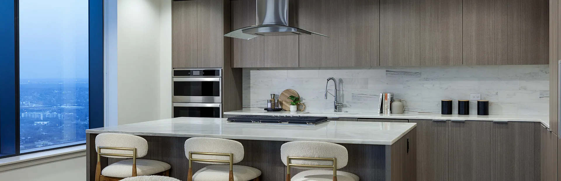 Sophisticated kitchen with modern design, featuring sleek cabinetry, a stylish island with bar seating, and expansive city views through large windows.