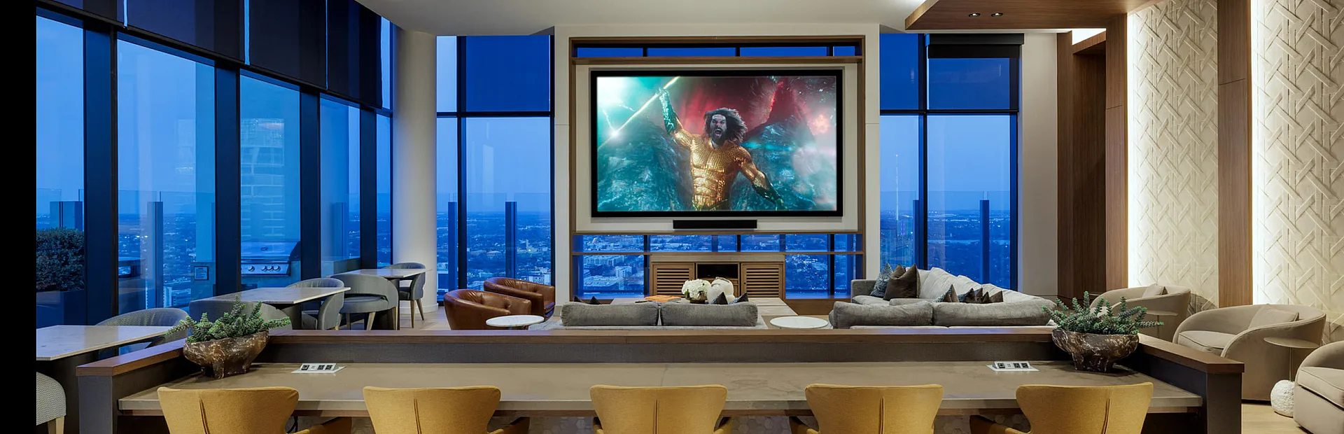 Stunning modern penthouse living area with panoramic city views, featuring a luxurious home theater setup and stylish seating arrangement.