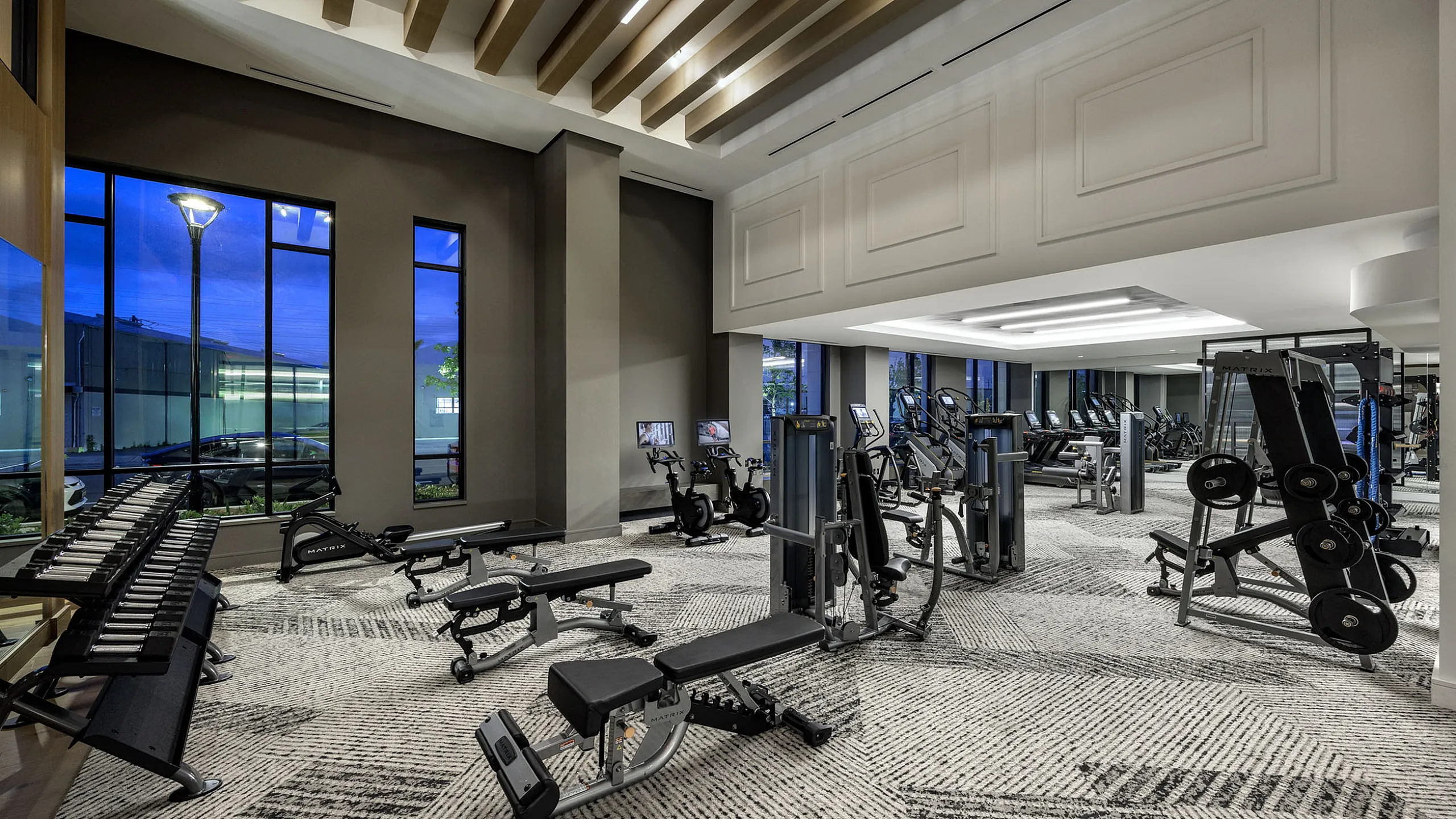 Modern fitness center with state-of-the-art exercise equipment, sleek design, and large windows overlooking a scenic view.