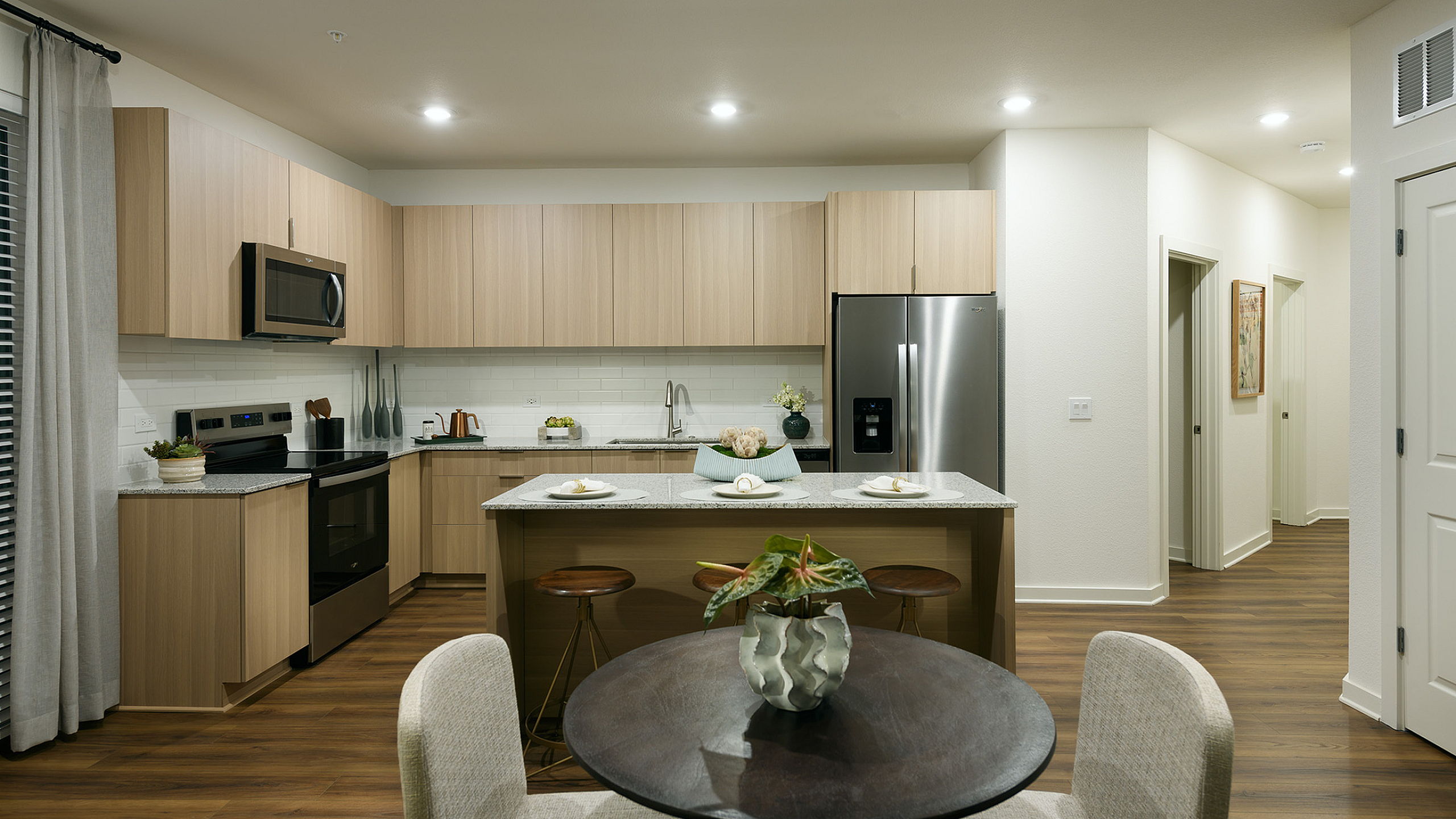 Modern kitchen with sleek wooden cabinetry, stainless steel appliances, and a chic dining area, perfect for stylish living.