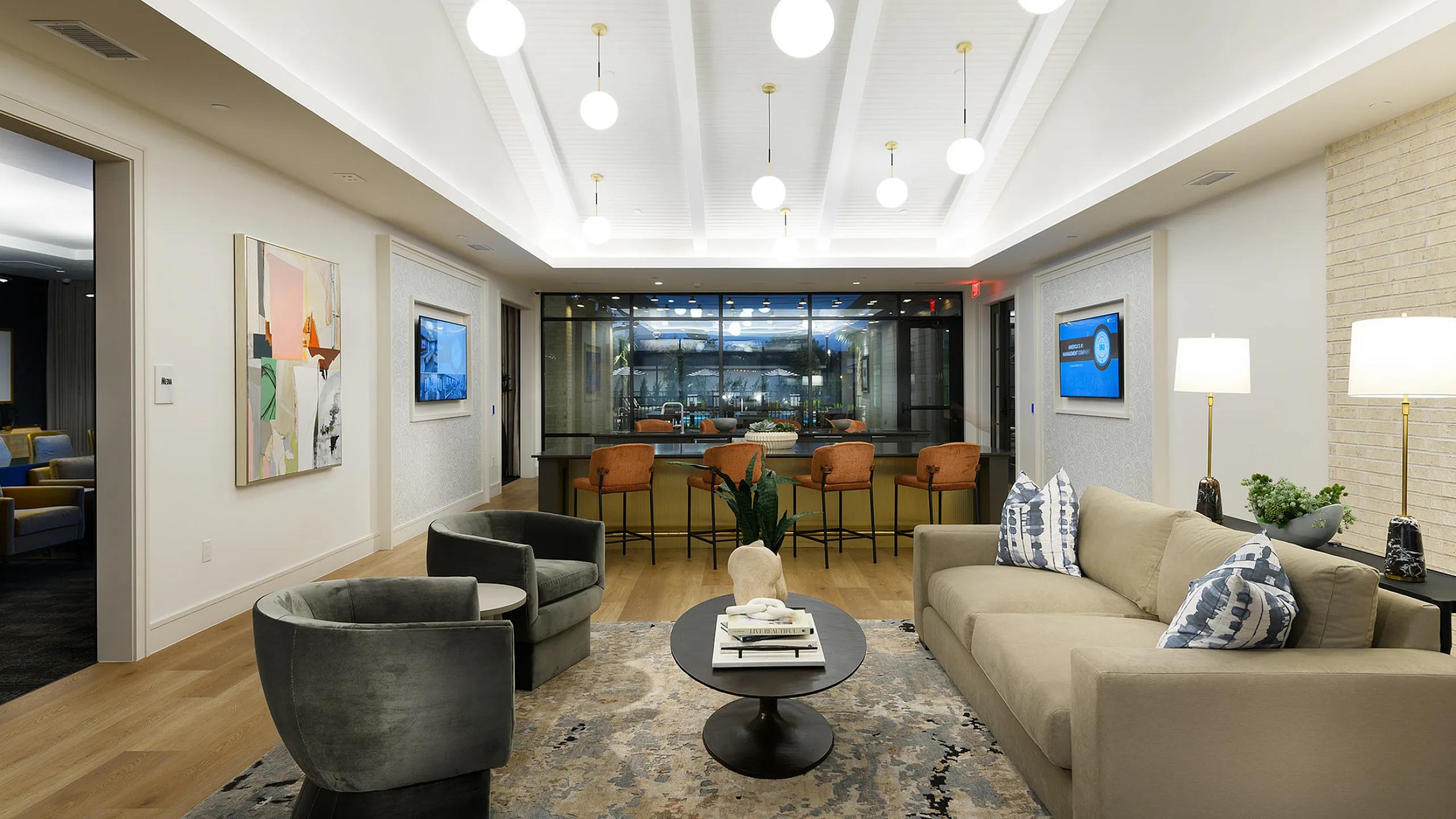 Elegant and modern living area with cozy seating, stylish coffee table, and luminous ceiling lights, overlooking a chic bar area.