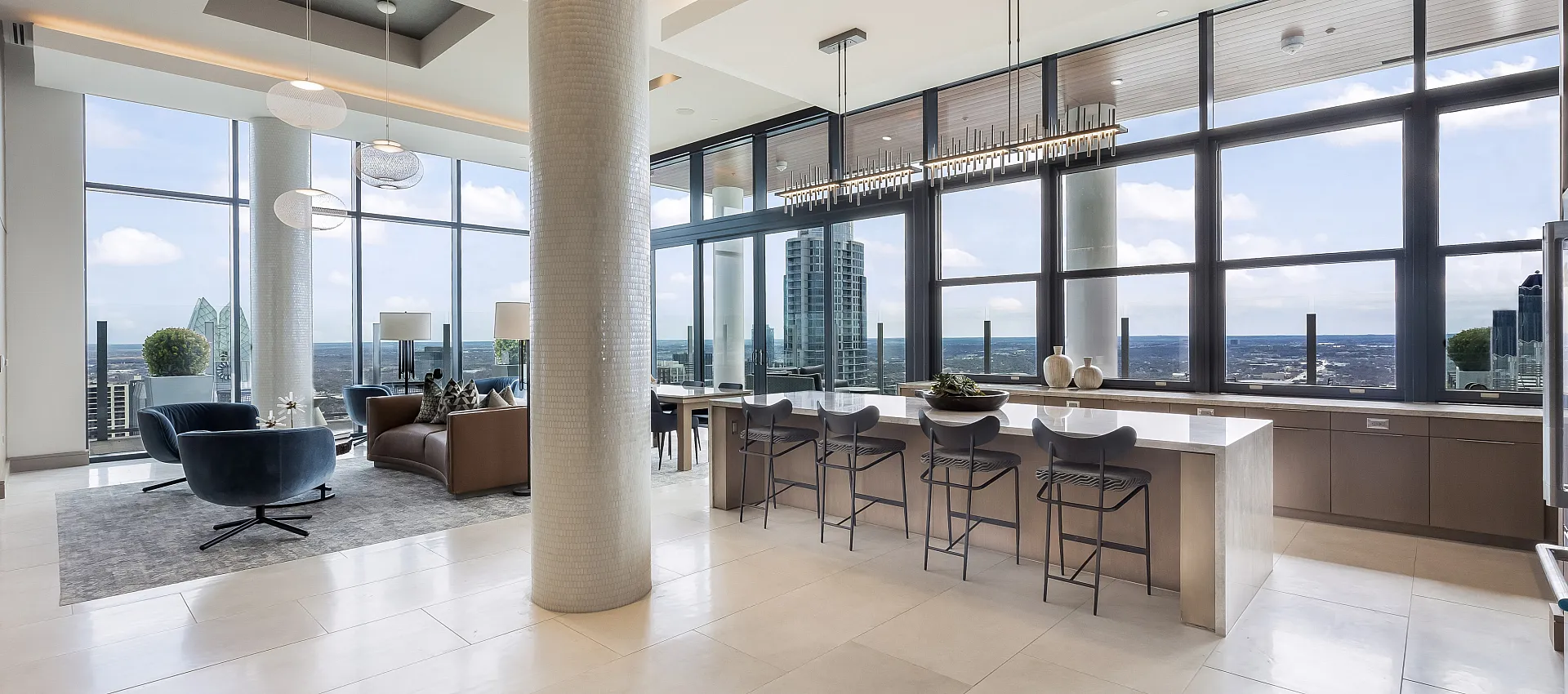 Modern open-concept living space with floor-to-ceiling windows, stunning city views, and a sleek kitchen with an island bar.