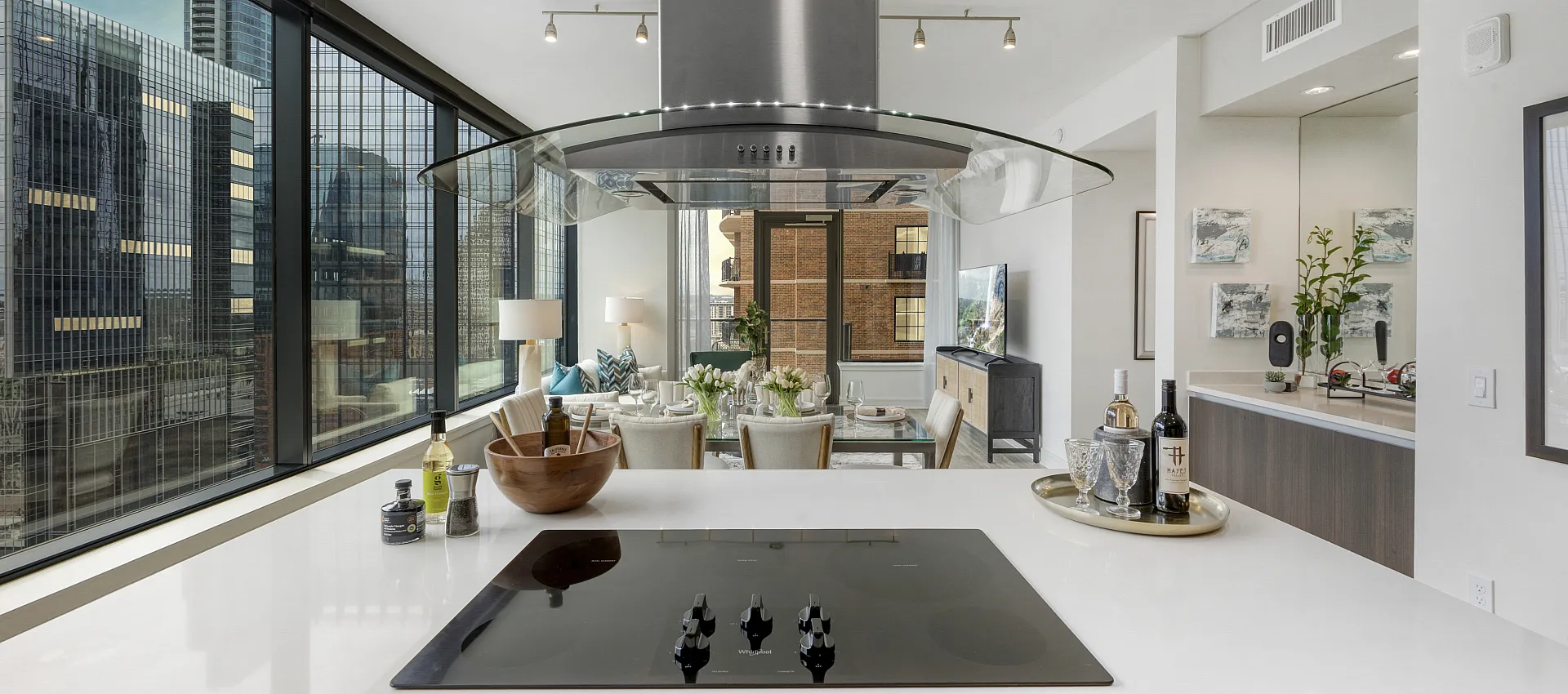Luxurious modern apartment with open-concept kitchen and dining area boasting stunning city views through floor-to-ceiling windows.