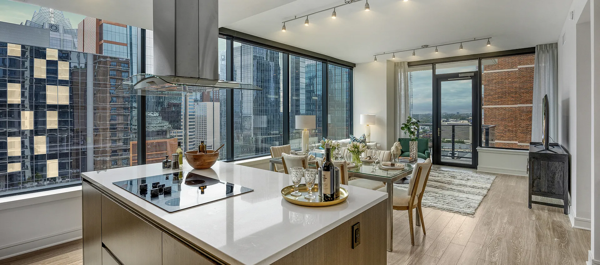 Modern open-concept kitchen and living area with stunning city views, featuring sleek countertops, elegant dining setup, and floor-to-ceiling windows.