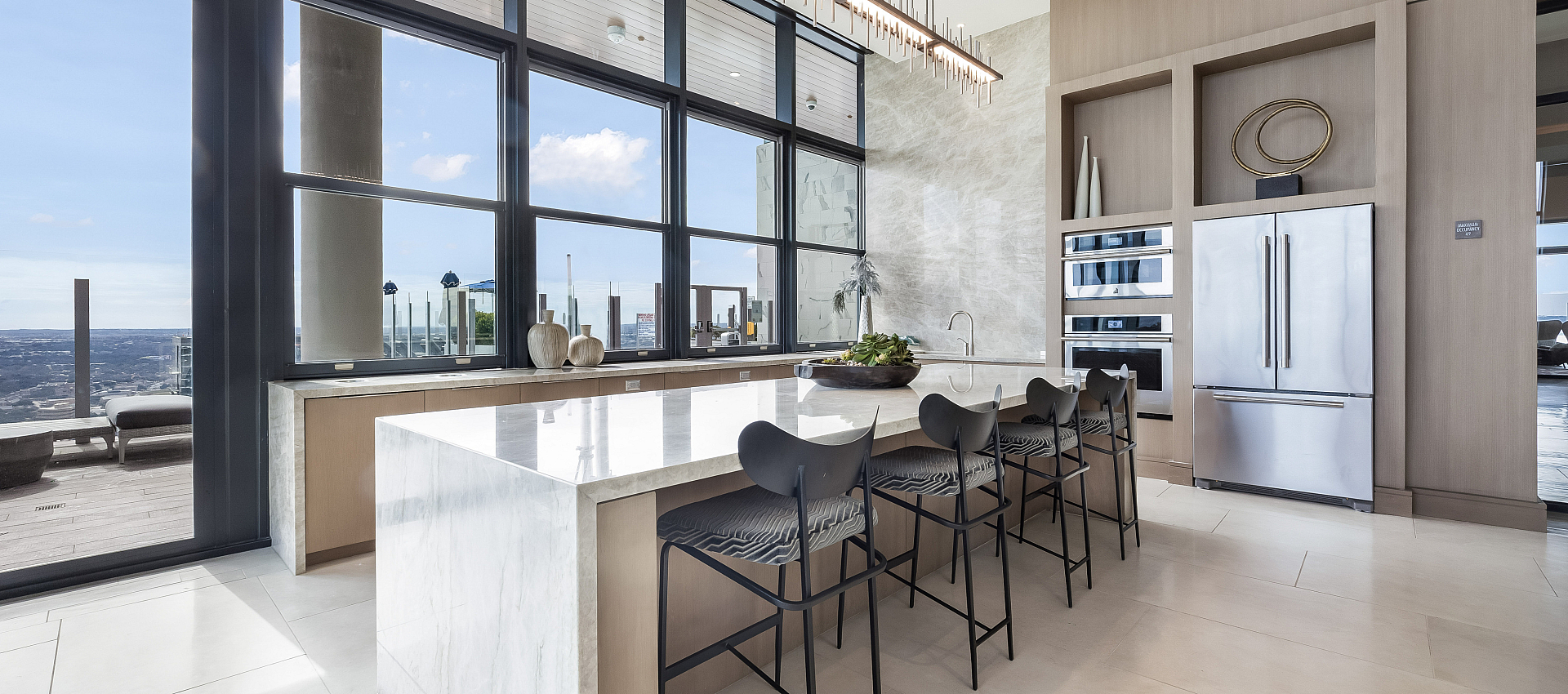 Sleek modern kitchen with an island and bar seating, offering panoramic city views through expansive windows.