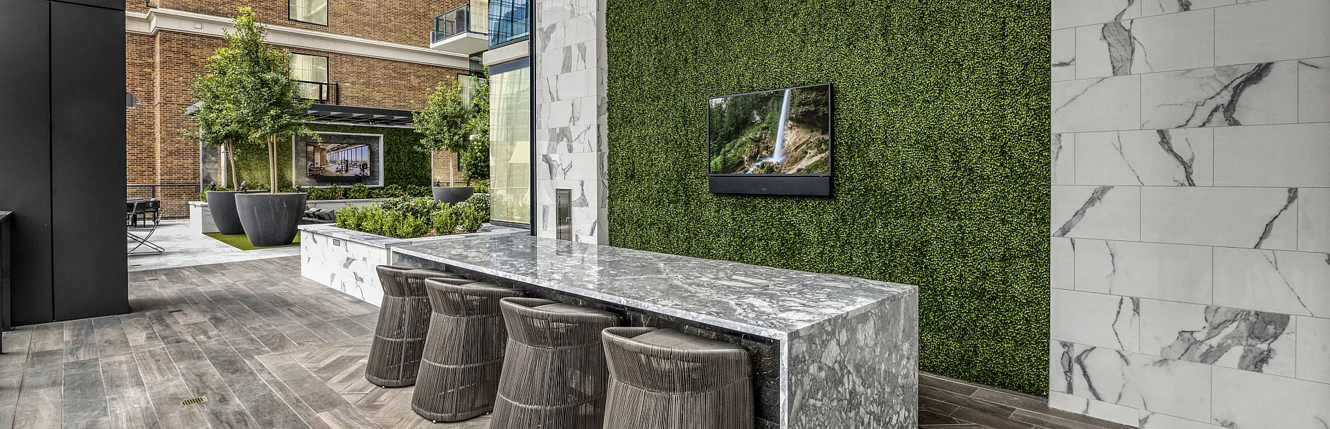 Elegant patio space featuring a chic marble countertop, cozy seating, and lush green wall amid stylish outdoor architecture.