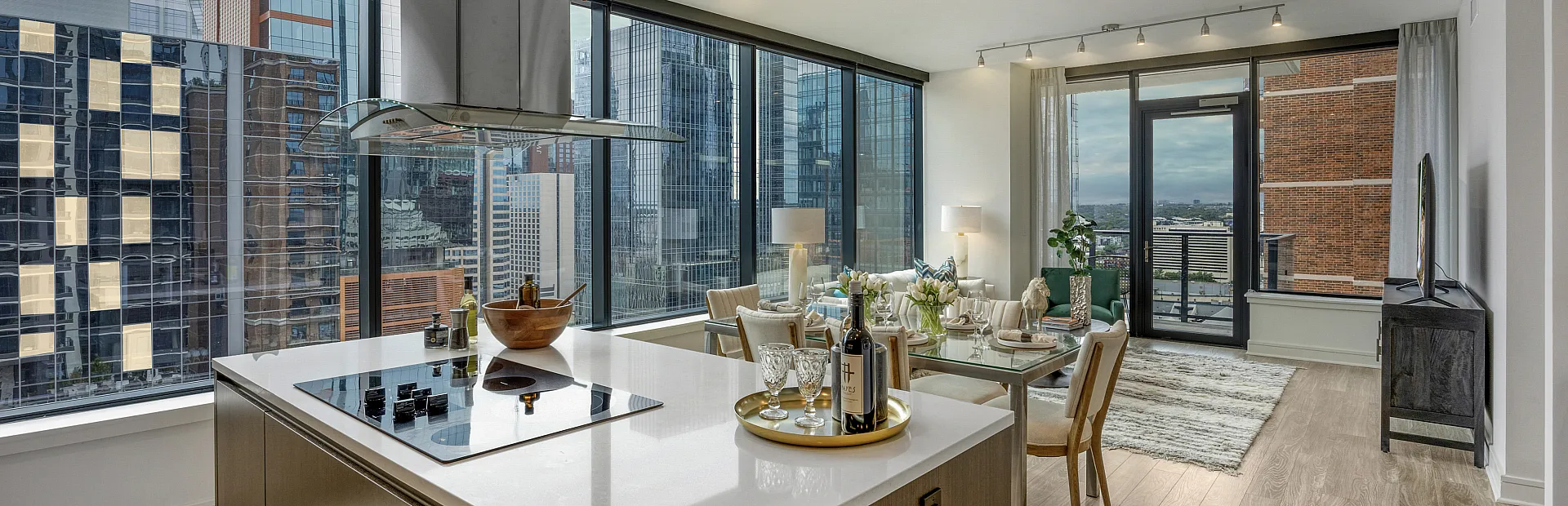 Modern city apartment with open-concept kitchen and dining area, featuring panoramic floor-to-ceiling windows and sleek contemporary design.