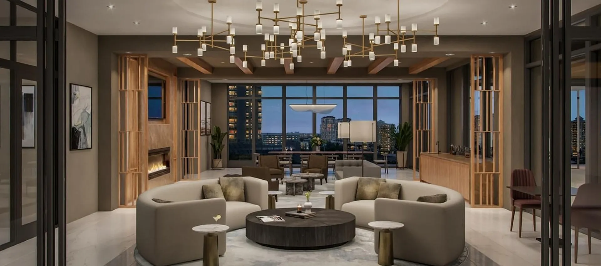 Luxurious modern living area with elegant chandeliers, cozy seating, a fireplace, and a stunning city view through floor-to-ceiling windows.