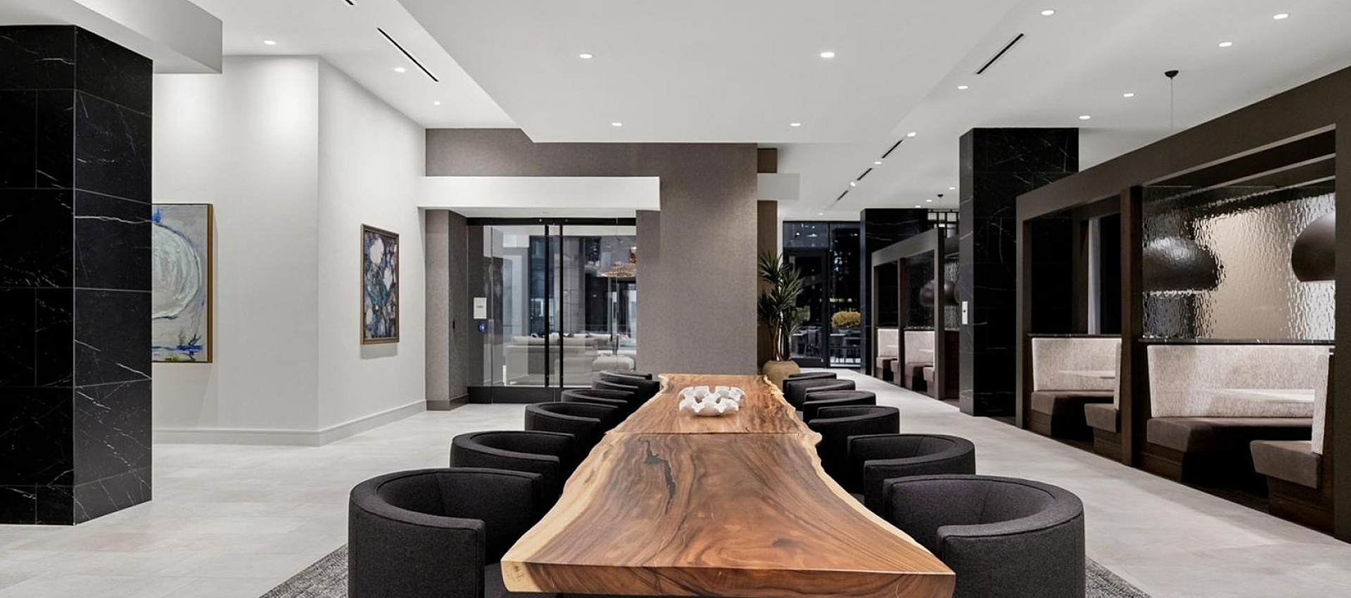 Chic and modern lobby featuring a striking wooden communal table, elegant seating, and stylish artwork, creating an inviting atmosphere.