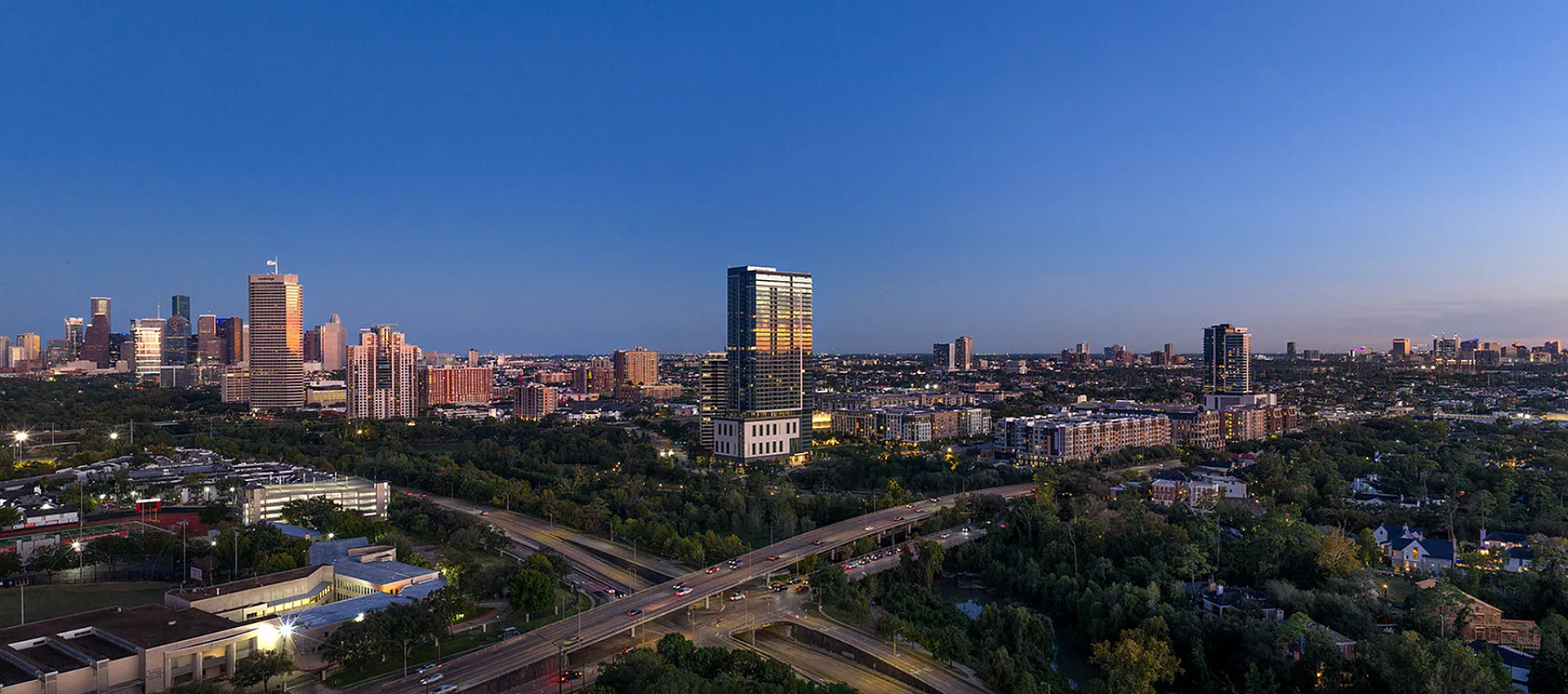 Stunning panoramic city skyline view at dusk, showcasing vibrant skyscrapers and lush green surroundings, perfect for an urban lifestyle.