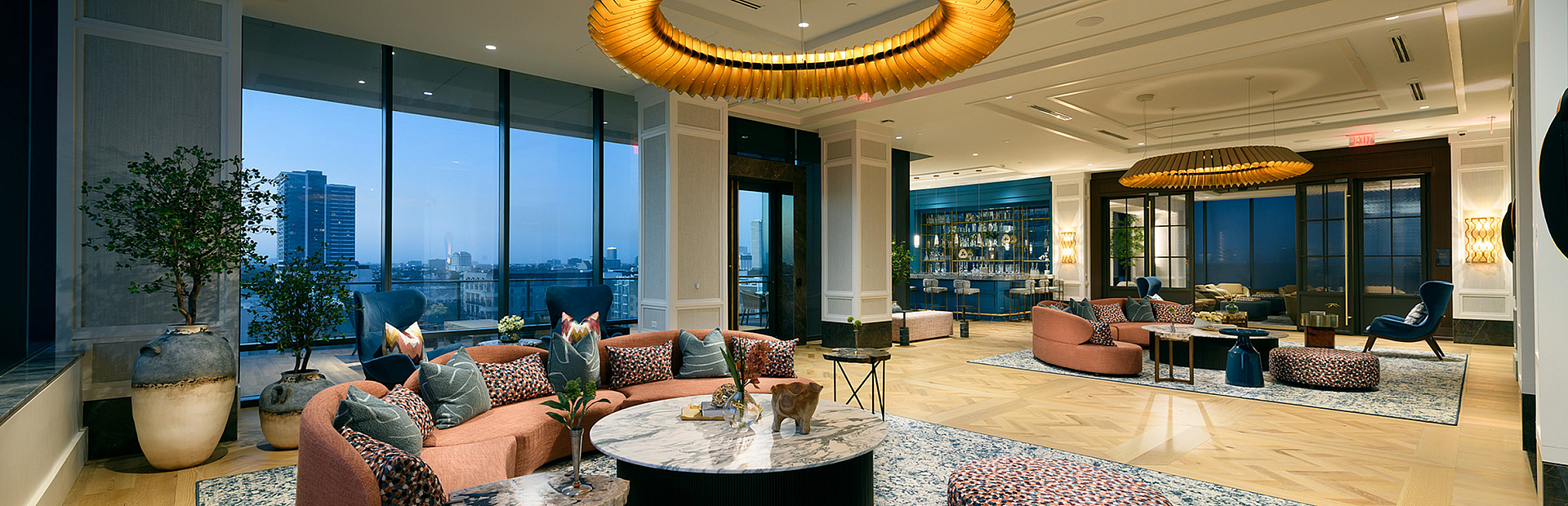 Luxurious and spacious living area with modern decor, featuring elegant lighting, plush seating, and panoramic city views through large windows.