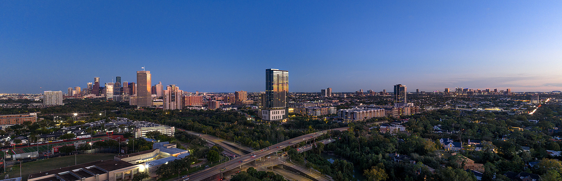 Breathtaking aerial cityscape at twilight highlighting a vibrant skyline with lush greenery and bustling streets below.