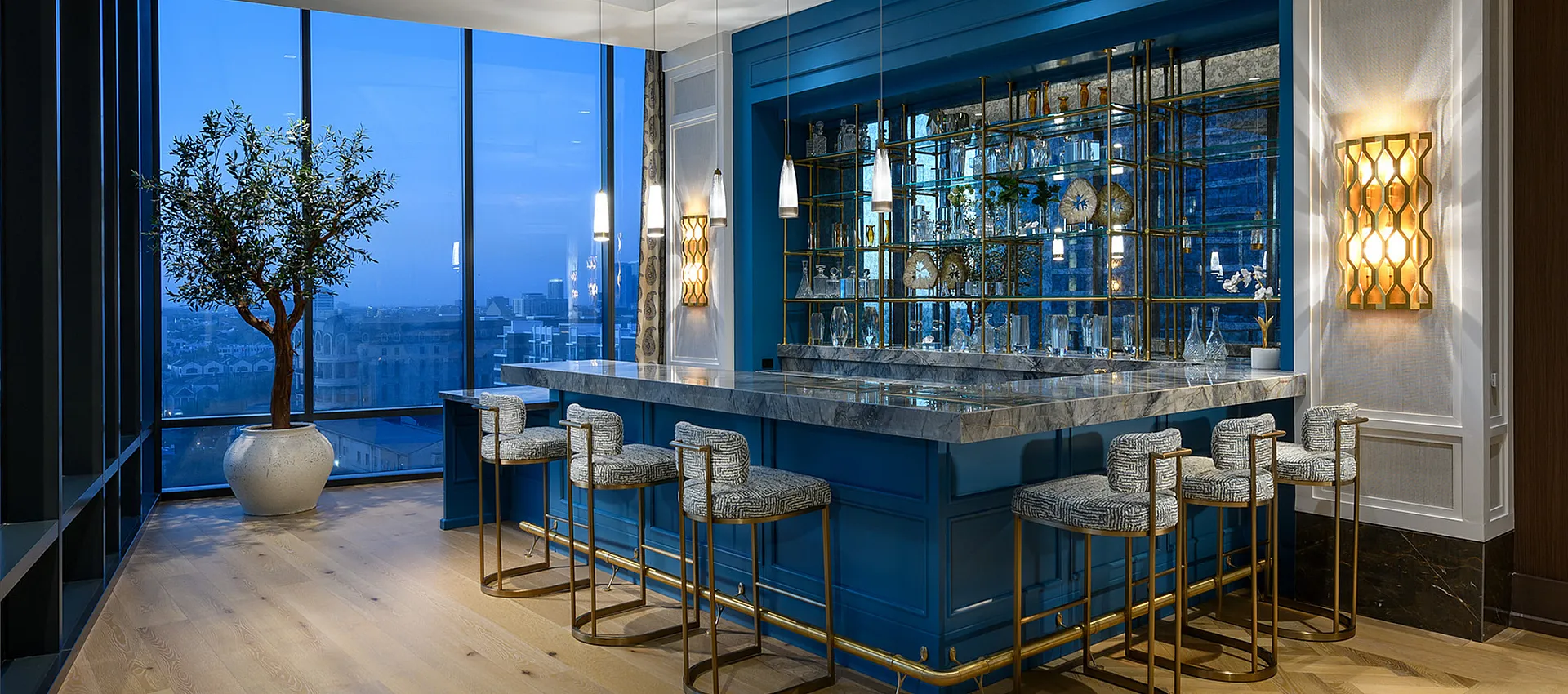 Luxurious home bar with elegant marble countertop and modern lighting, featuring stylish bar stools and a stunning city view.