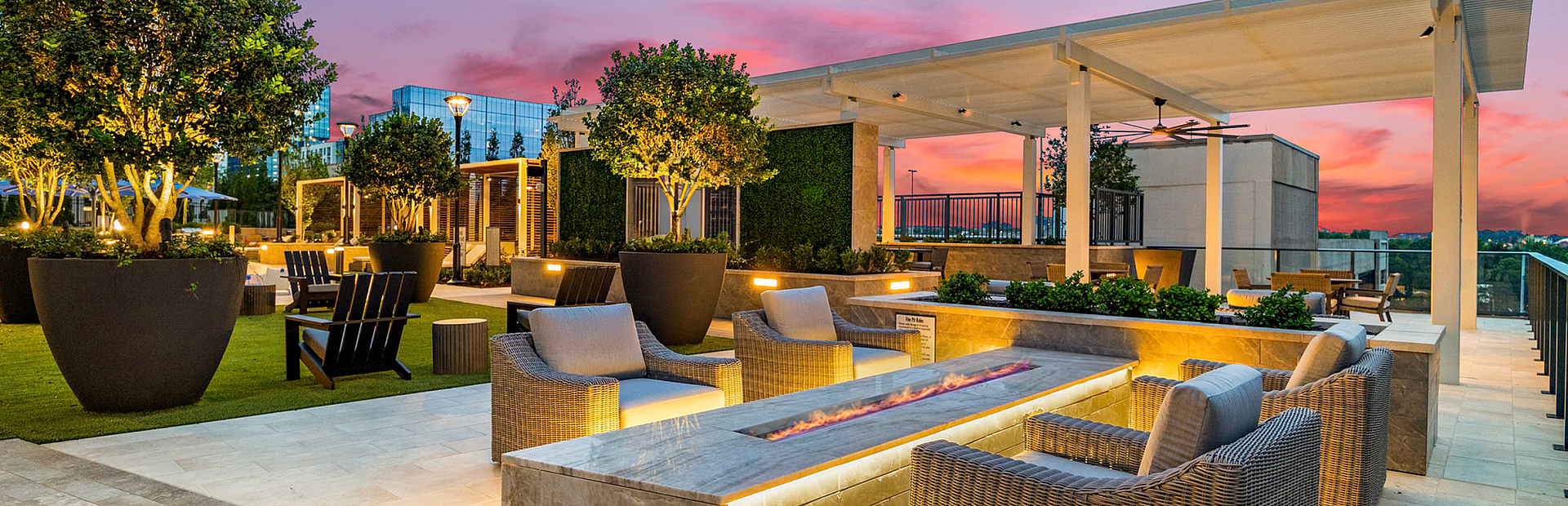 Luxurious rooftop terrace at sunset with cozy seating, elegant firepit, and lush greenery, perfect for relaxation and entertaining.