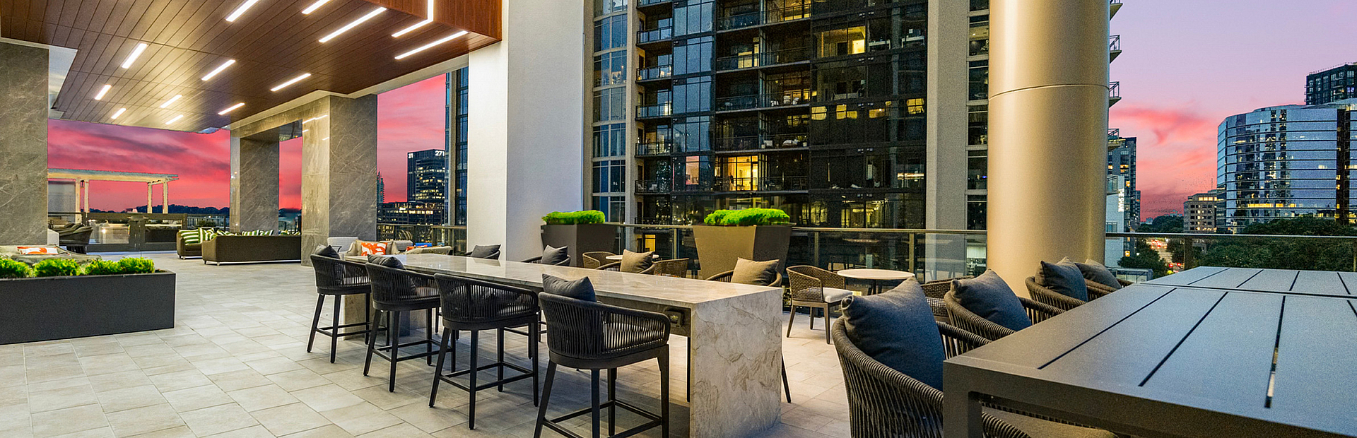 Modern outdoor terrace with stylish seating and vibrant sunset views in a luxury apartment building.