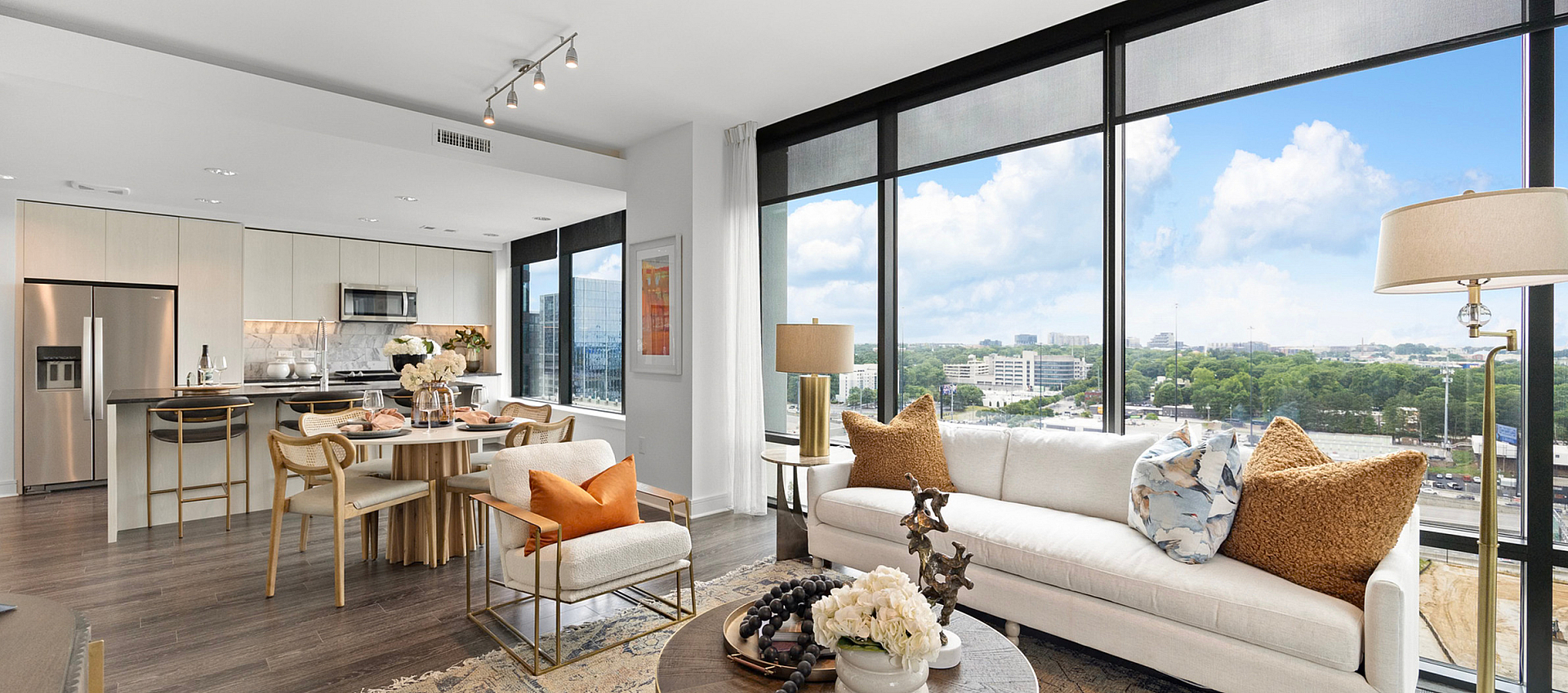Luxurious open-plan apartment with floor-to-ceiling windows, modern kitchen, stylish dining area, and cozy living space offering breathtaking city views.