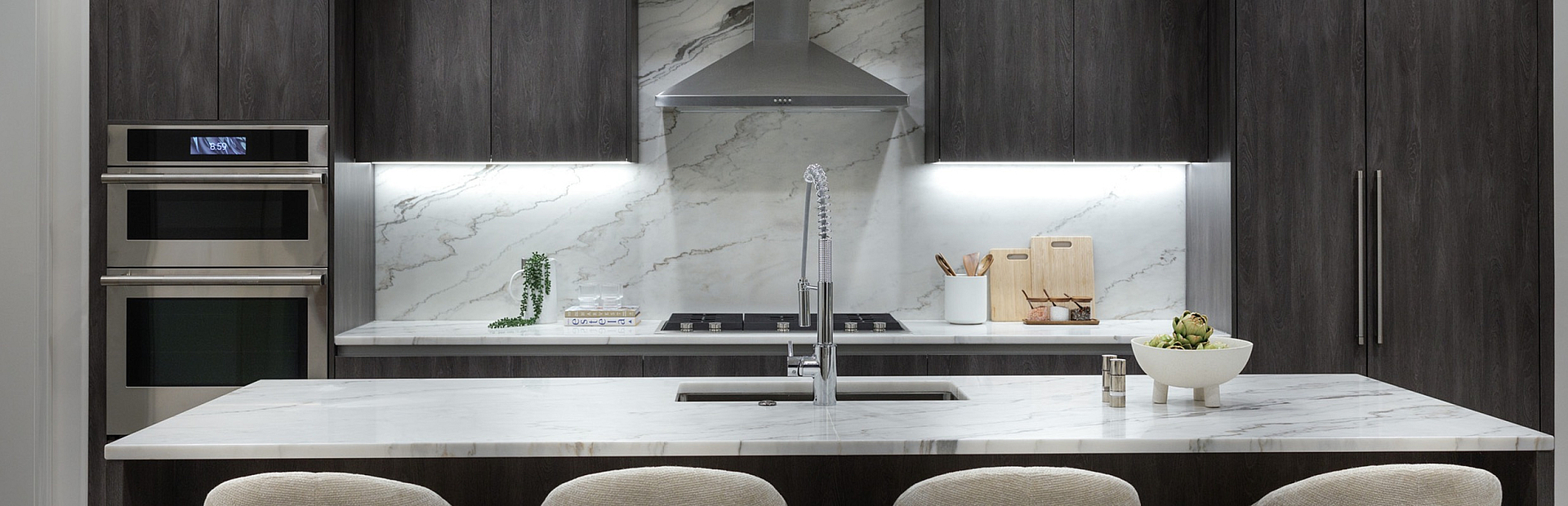Sleek modern kitchen with elegant marble backsplash, dark cabinetry, and a stylish island with chic bar stools.