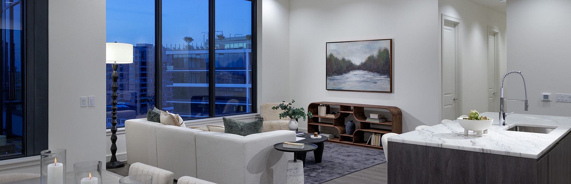 Chic open-concept living area featuring modern decor, a cozy sectional sofa, and a sleek kitchen island with elegant lighting.
