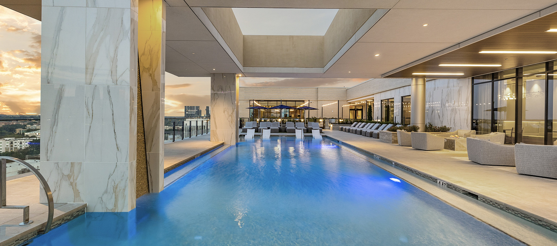 Luxurious rooftop pool area with stylish lounge seating and stunning sunset views, offering a serene urban oasis.
