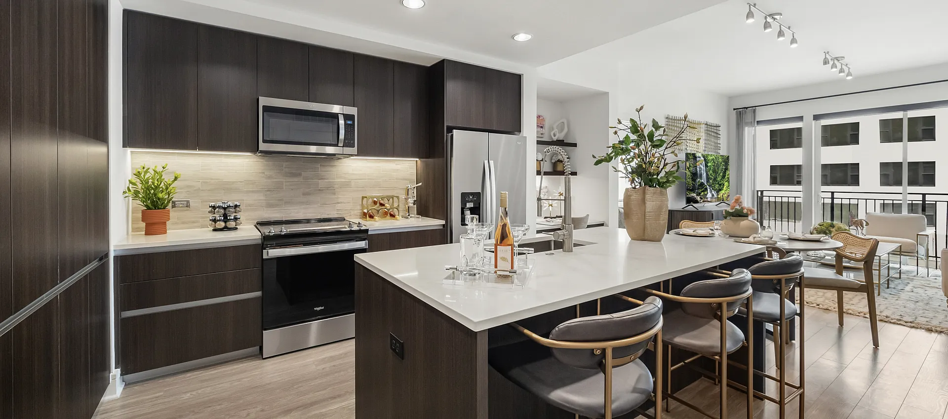 Modern kitchen with sleek dark cabinetry, stainless steel appliances, and elegant breakfast bar in a bright, open-concept apartment.