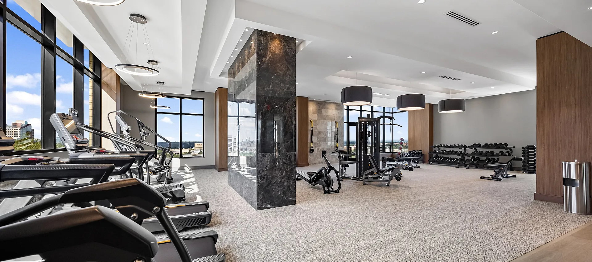 Luxurious fitness center featuring modern equipment, panoramic city views, and elegant design for an elevated workout experience.