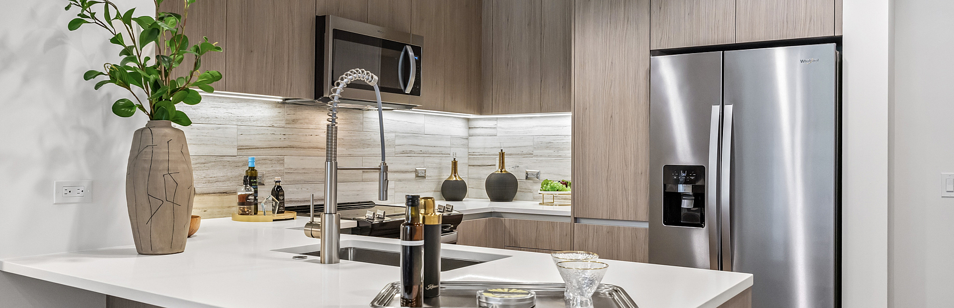 Modern kitchen with sleek stainless steel appliances, stylish white countertops, and wood cabinetry, creating a chic culinary space.