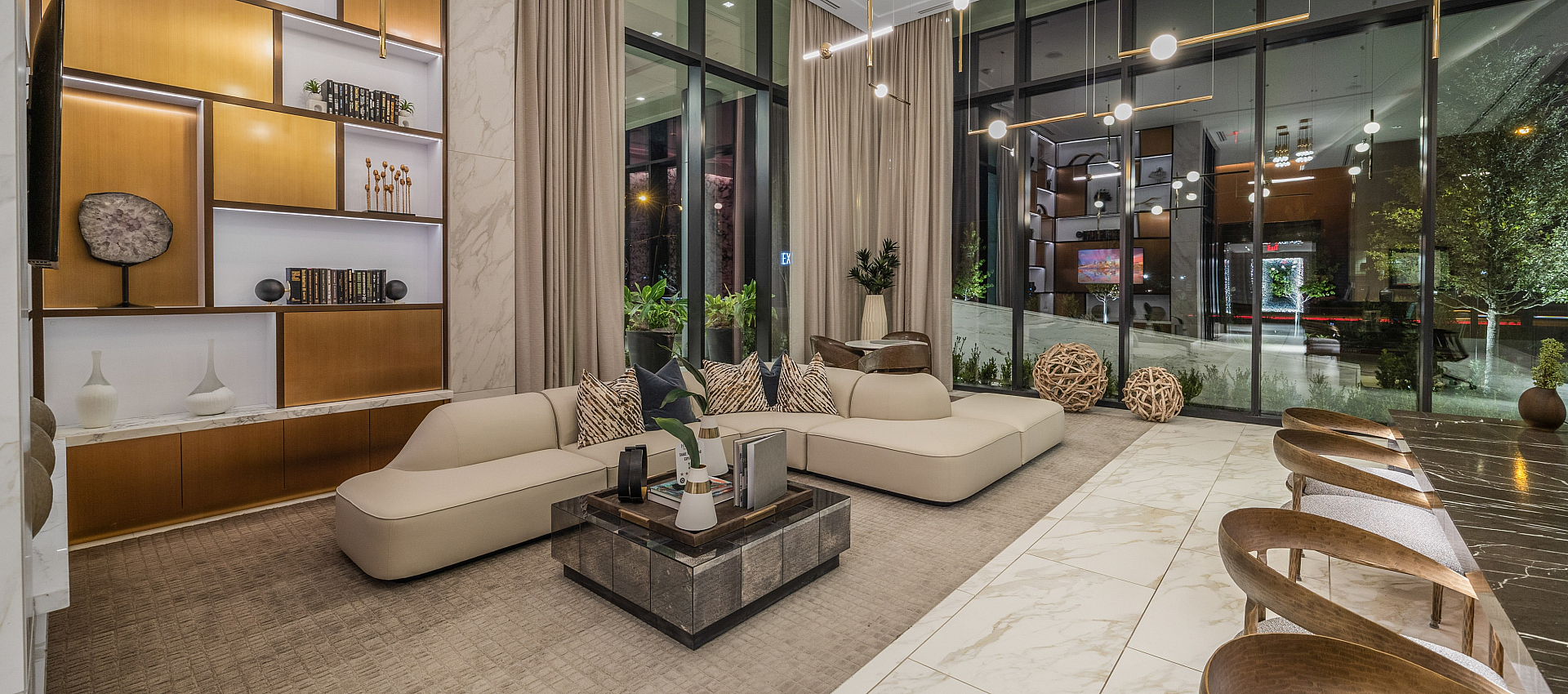 Luxurious open-plan living room with modern decor, plush seating, elegant shelving, and floor-to-ceiling windows offering stunning views.