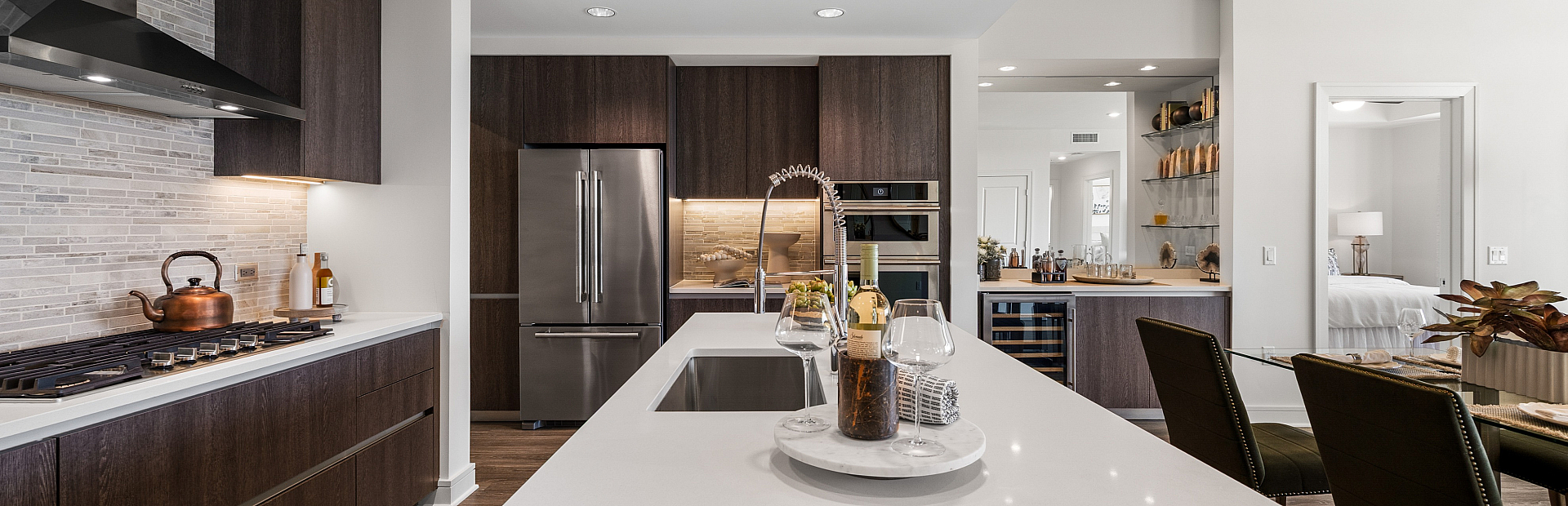 Luxurious modern kitchen with sleek dark cabinetry, stainless steel appliances, and elegant stone backsplash, offering an inviting space for culinary creativity.