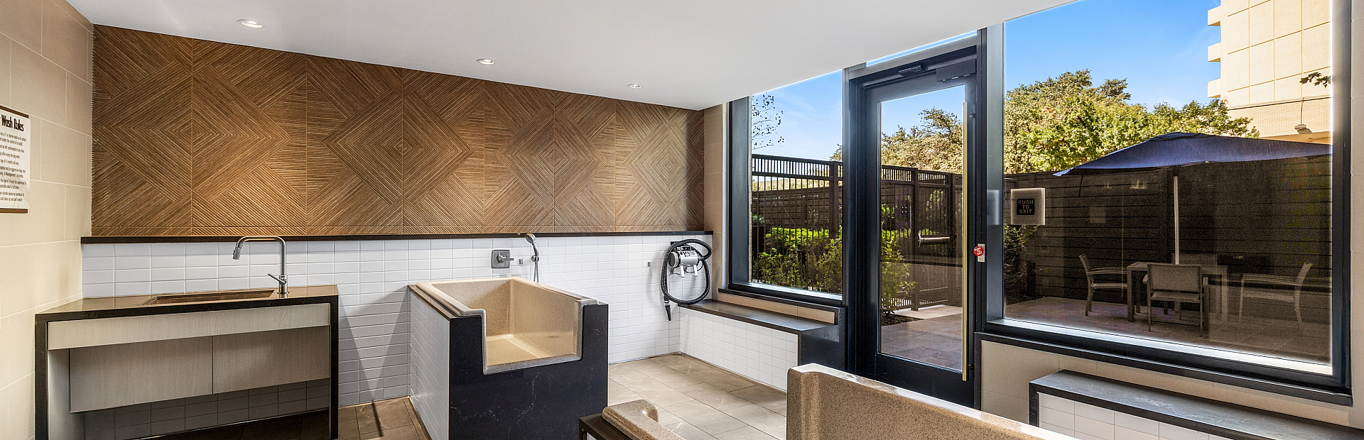 Modern pet washing station with elegant design, featuring a sleek sink, stylish tile accents, and large windows offering natural light.