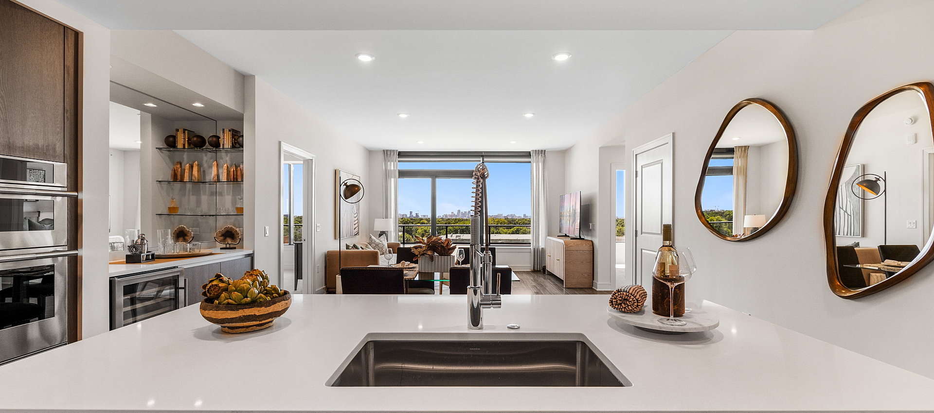 Modern open-concept kitchen with sleek appliances and inviting living area featuring panoramic city views through large windows.